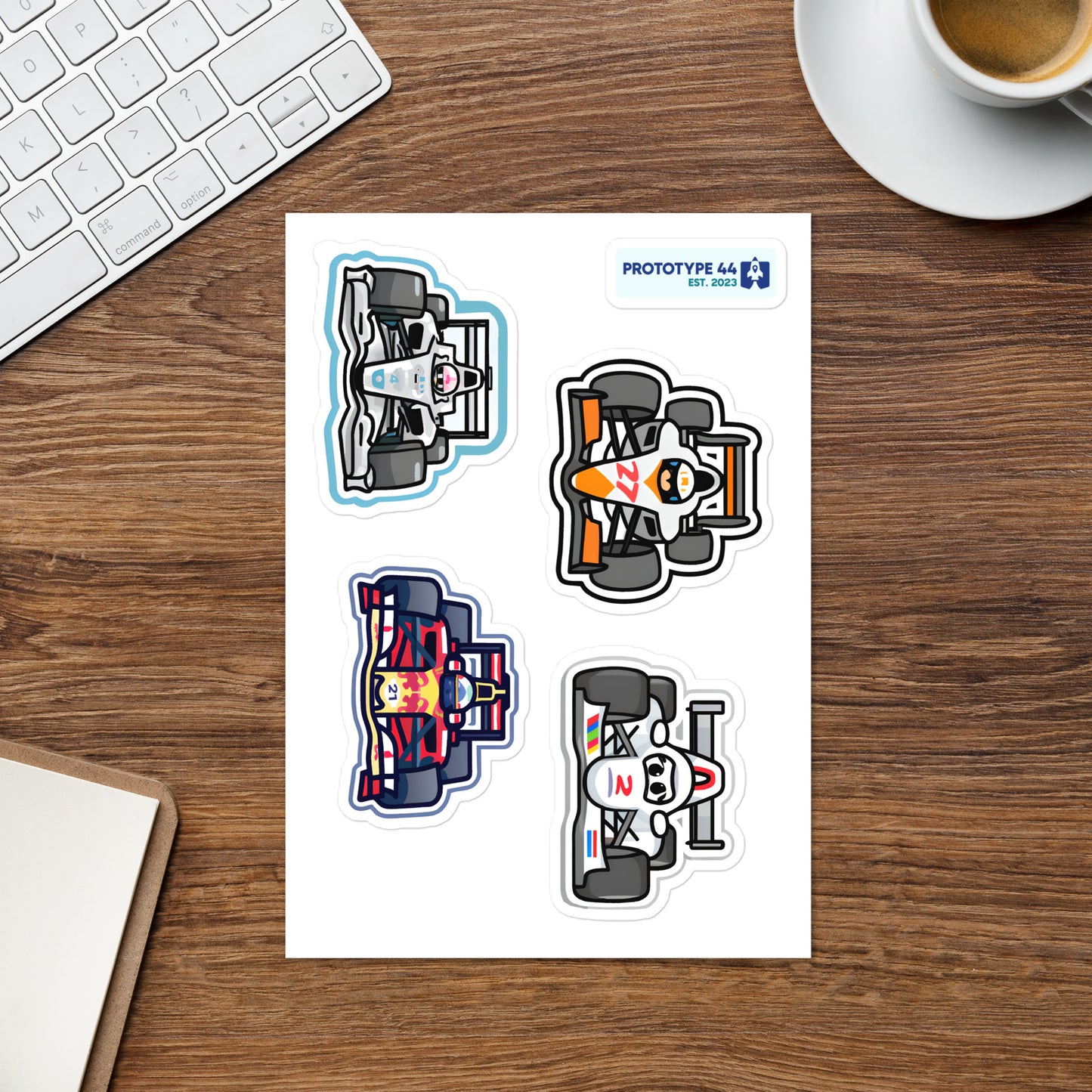 F1 sticker sheet on wood table with coffee cup, keyboard etc.